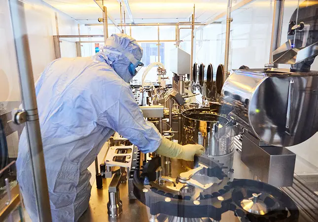 Steriscience operator in full cleanroom gowning working at a sterile compounding vessel