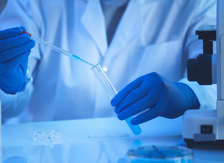 Gloved hands using a pipette to transfer a sample during formulation development